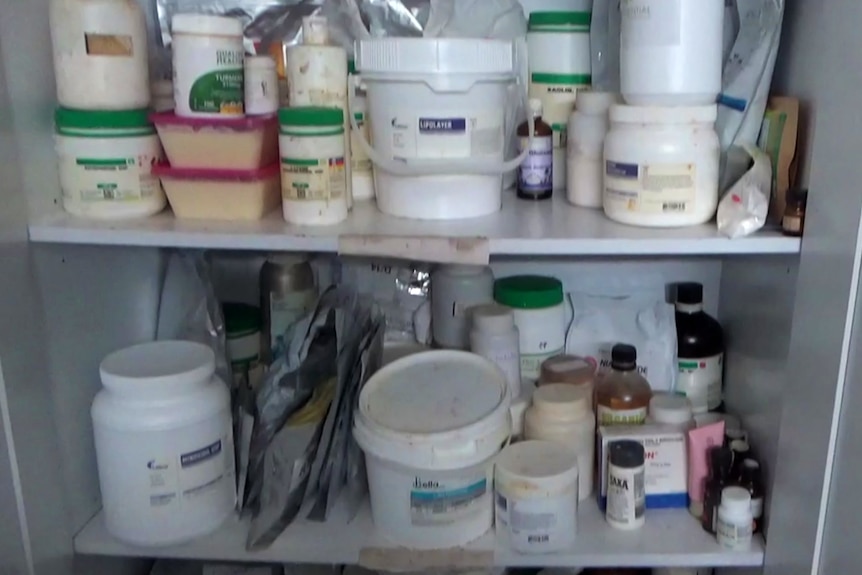 Shelves filled with various chemical containers, stored in a disorderly manner.